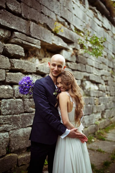 Atemberaubende Braut lächelt, von einem Bräutigam umarmt — Stockfoto