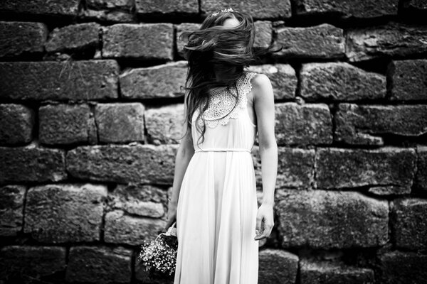 Hair hides lady's face while she stands behind a stone wall