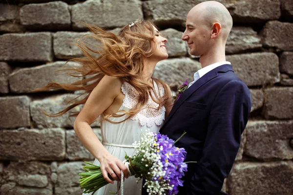 Sposa sorride guardando uno sposo mentre il vento le soffia i capelli — Foto Stock