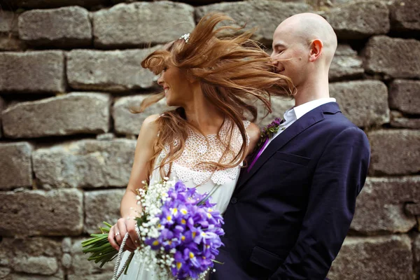 Bräutigam umarmt eine Braut, während sie mit ihren Haaren spielt — Stockfoto