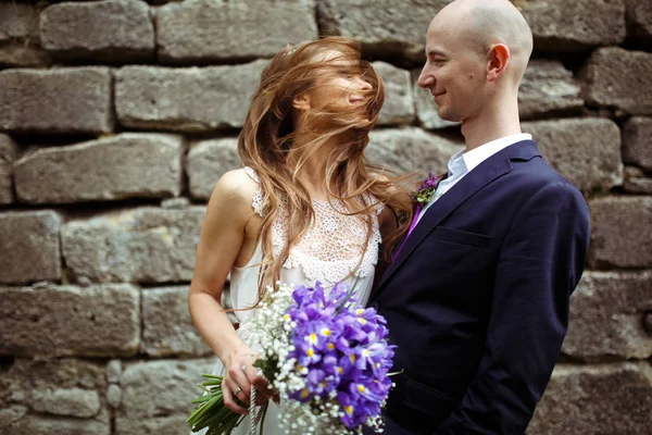 Braut legt sich die Haare um das Gesicht, während der Bräutigam sie hält — Stockfoto