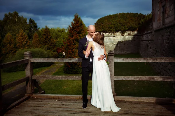 Ett bröllop par kyssar stående bakom ett gammalt slott — Stockfoto