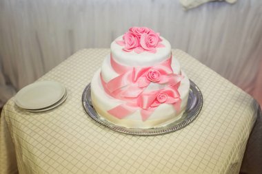Pembe ve beyaz şeritler ve li ile dekore edilmiş güzel düğün pastası