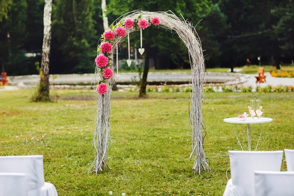 Ein schlichter Hochzeitsaltar mit rosafarbenen Fahnen steht auf dem Feld — Stockfoto