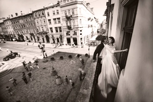 Stylish wedding couple kisses on the balcony in the old city — Stock Photo, Image