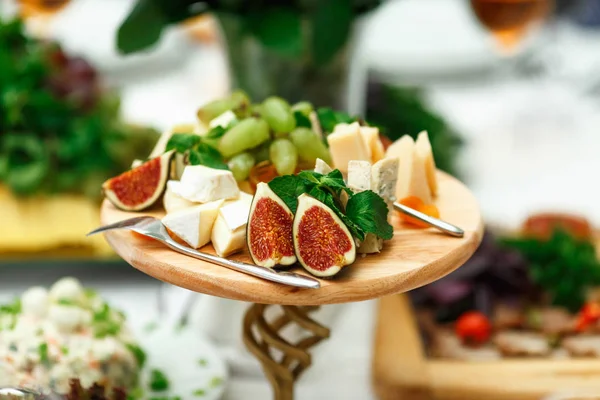 Frutos exóticos e queijo estão cortados em uma bandeja de madeira — Fotografia de Stock