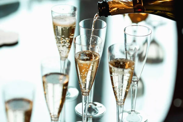 Champán vierte en las copas de vino en una mesa de cristal — Foto de Stock