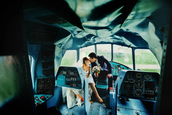 Bruidegom kussen een bruid zitten in een oude helikopter — Stockfoto