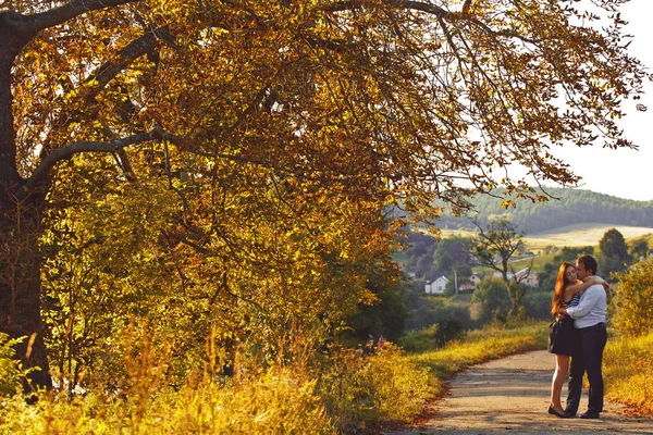 Liefde tussen de herfst bomen - coule knuffels op de weg in het park — Stockfoto