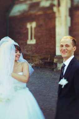 Gelin ve damat ayakta eski bir Katedrali ayrı gülümse 