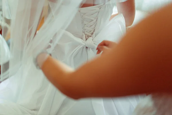 Las manos de la mujer ata el lazo en el vestido de boda — Foto de Stock