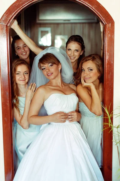 Невеста выглядит потрясающе, когда позирует с девушками в дверях — стоковое фото