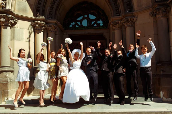 Mariée, marié et amis sautent devant une grande porte de la — Photo