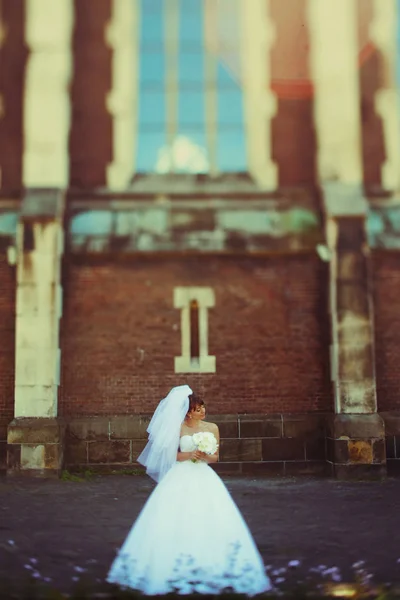 Bride enjoys a wind posing behind a cathedral — Stock Photo, Image