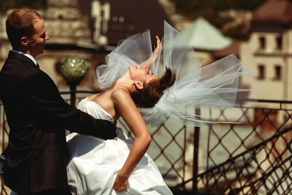 Nevěsta se ohýbá v rukou ženicha a její závoj šíří po — Stock fotografie