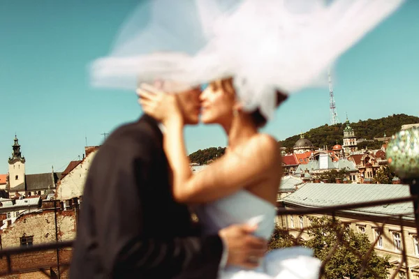 Imagem turva de recém-casados se beijando na frente do telhado de Lviv — Fotografia de Stock