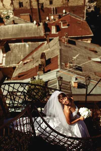 Vestido de novia se encuentra en las escaleras de caracol mientras disfruta de sunshin — Foto de Stock