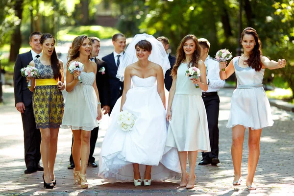 Bridesmids pohled legrační, zatímco pózuje s nevěstou v parku — Stock fotografie