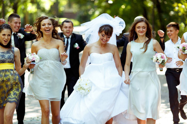 Stunning bride enjoys a walk with friends in the summer park 