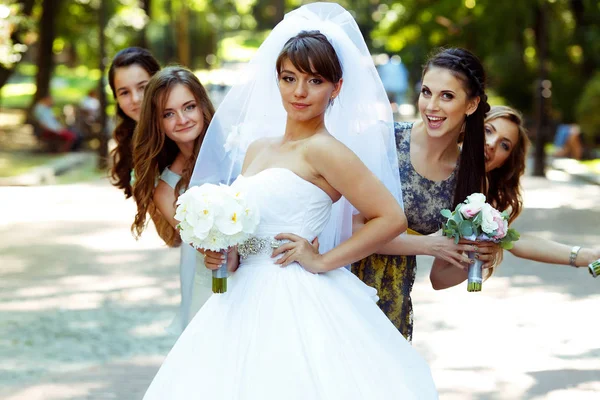 Damas de honra se escondem atrás de uma noiva enquanto ela está em primeiro plano — Fotografia de Stock