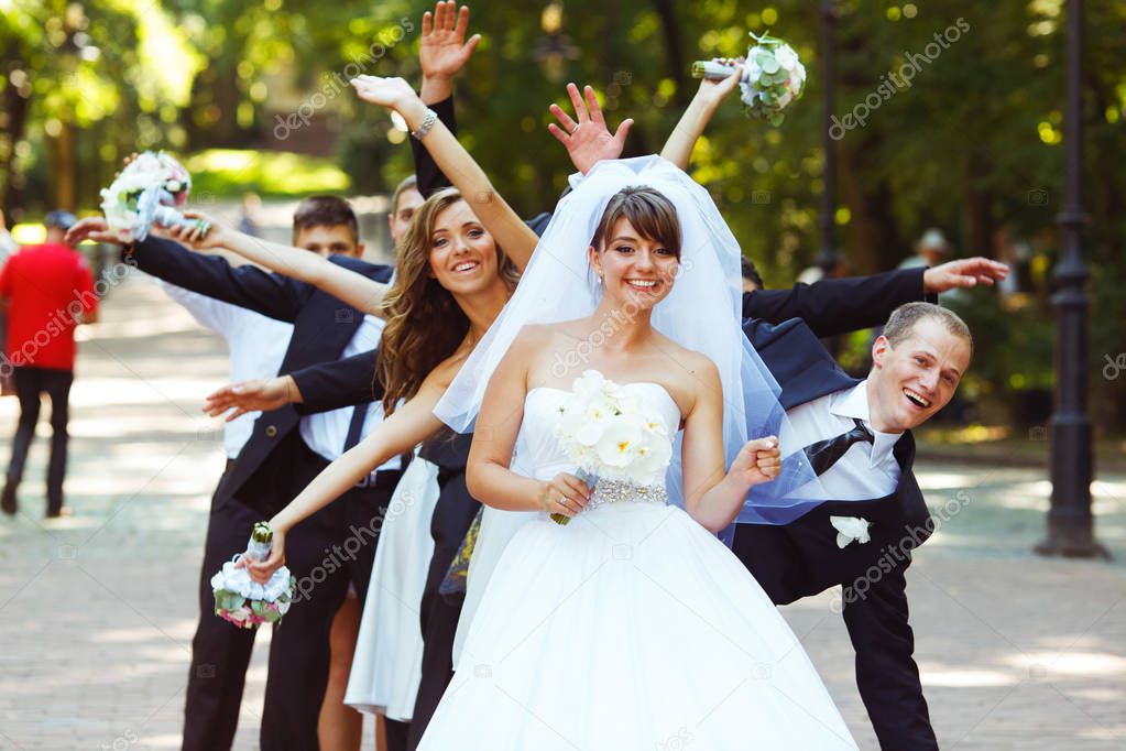 Groom and friends stand in the ray behind a bride dancing in the