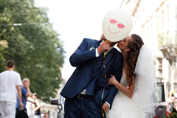 Novia besa la mejilla de un novio mientras se esconde detrás de un globo — Foto de Stock