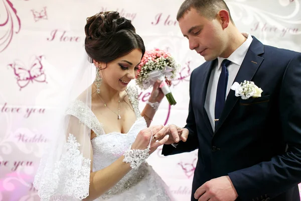 As noivas usam anéis perto do banner do casamento — Fotografia de Stock