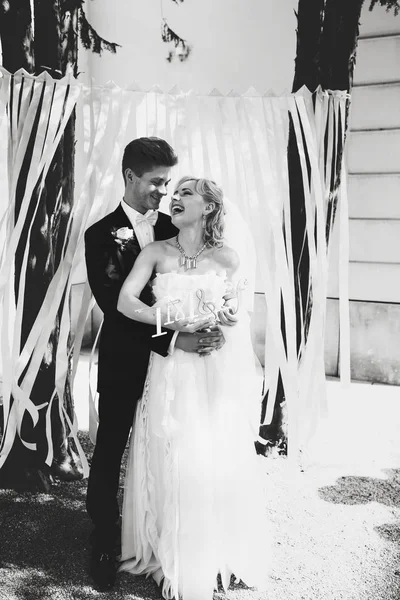 A black and white of smiling newlyweds standing in the garden — Stock Photo, Image