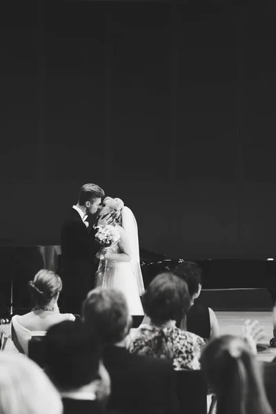 Bruden och brudgummen kyssa stående på scenen — Stockfoto
