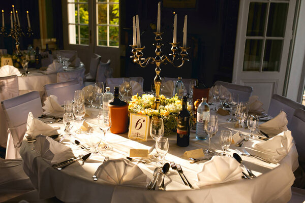 Steel candleholder stands in the middle of a round dinner table 