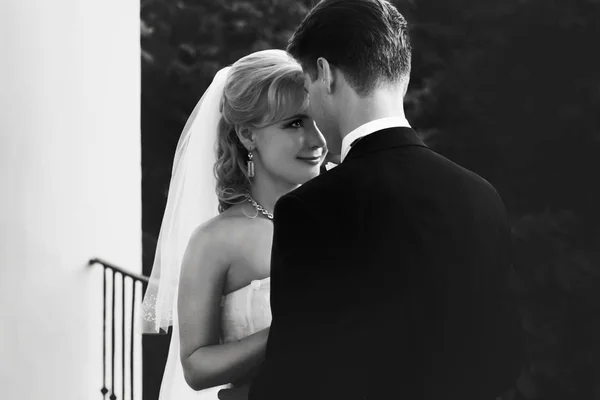 Невеста восхищается женихом, склоняющимся к нему на балконе — стоковое фото