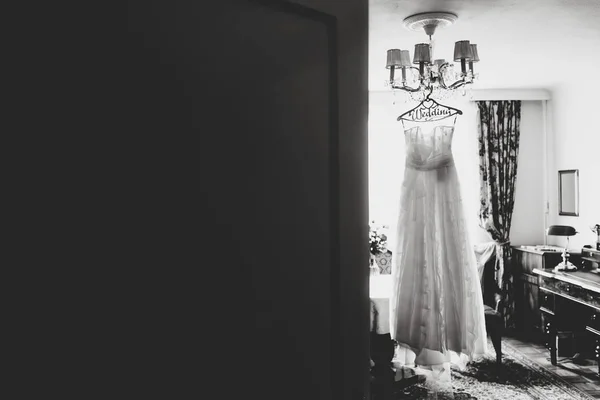 一手に掛かっている白いドレスにドアの後ろから見て — ストック写真