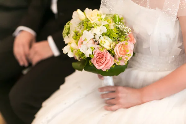 Mariée tient beau bouqet de mariage assis derrière un marié — Photo