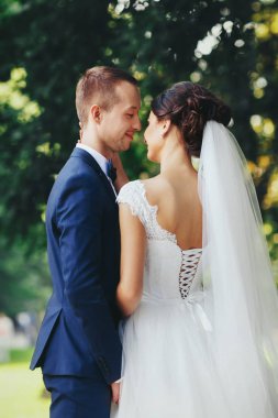 Güzel gelin damadın boyun stnading bir yeşil ağaç altında dokunur 