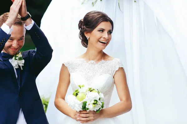 Жених и невеста выглядят радостными, стоя за алтарем — стоковое фото