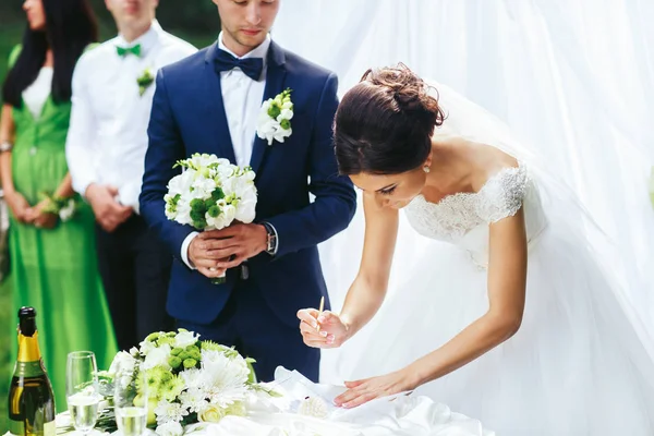 Braut unterschreibt Verlobungspapier hinter Bräutigam — Stockfoto