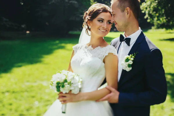 Mariée se penche vers un marié debout avec lui dans le jardin — Photo