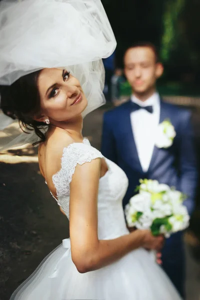 Mariée regarde par-dessus son épaule et sourit tandis que le marié attend sur le th — Photo