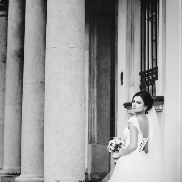 Nádherná nevěsta představuje mezi pilíři staré budovy — Stock fotografie