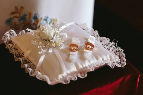 Golden wedding rings lie on the white silk pillow — Stock Photo, Image