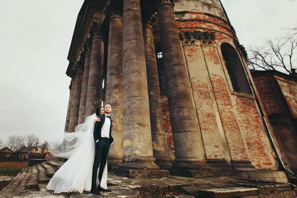 Una mirada desde abajo en la impresionante pareja de boda posando detrás de un — Foto de Stock