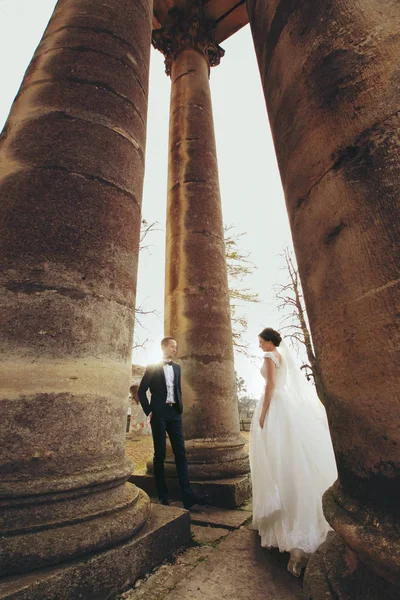 Grorgeous esküvői pár régi székesegyház pillérei között áll — Stock Fotó