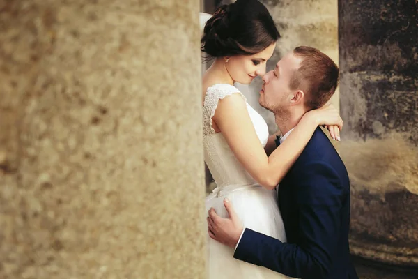 Bruden beundrar en brudgum som står mellan pelarna — Stockfoto