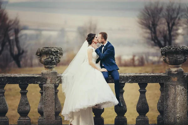 Groom beija uma noiva sentada com ela na varanda com um grea — Fotografia de Stock