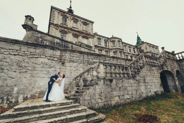 Noivo dobra noiva em pé nas escadas para a pedra velha c — Fotografia de Stock