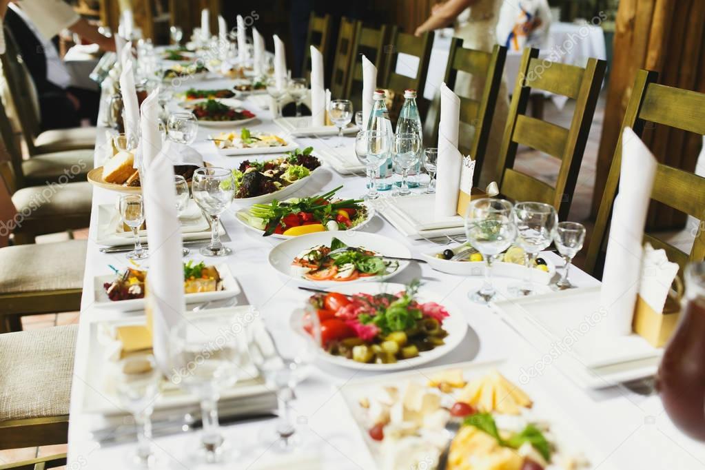 Green salads lie on white plates on the dinner table