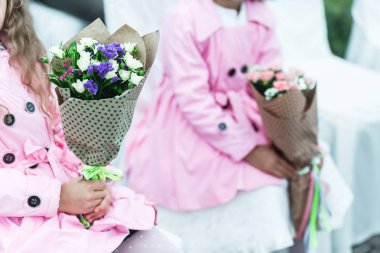 Pembe kat olarak küçük kızlar bouqu holding beyaz iskemlede oturmak