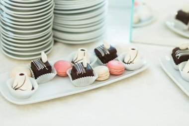Çikolata ve macaroons ve kare plaka üzerinde yalan 
