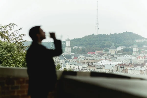 Hombre bebe champán en el balcón con gran paisaje urbano detrás —  Fotos de Stock