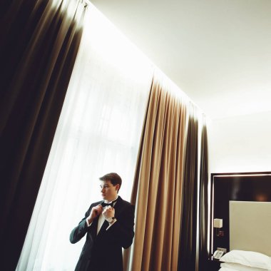 Damat parlak otel odasında bir papyon ayakta ayarlar 